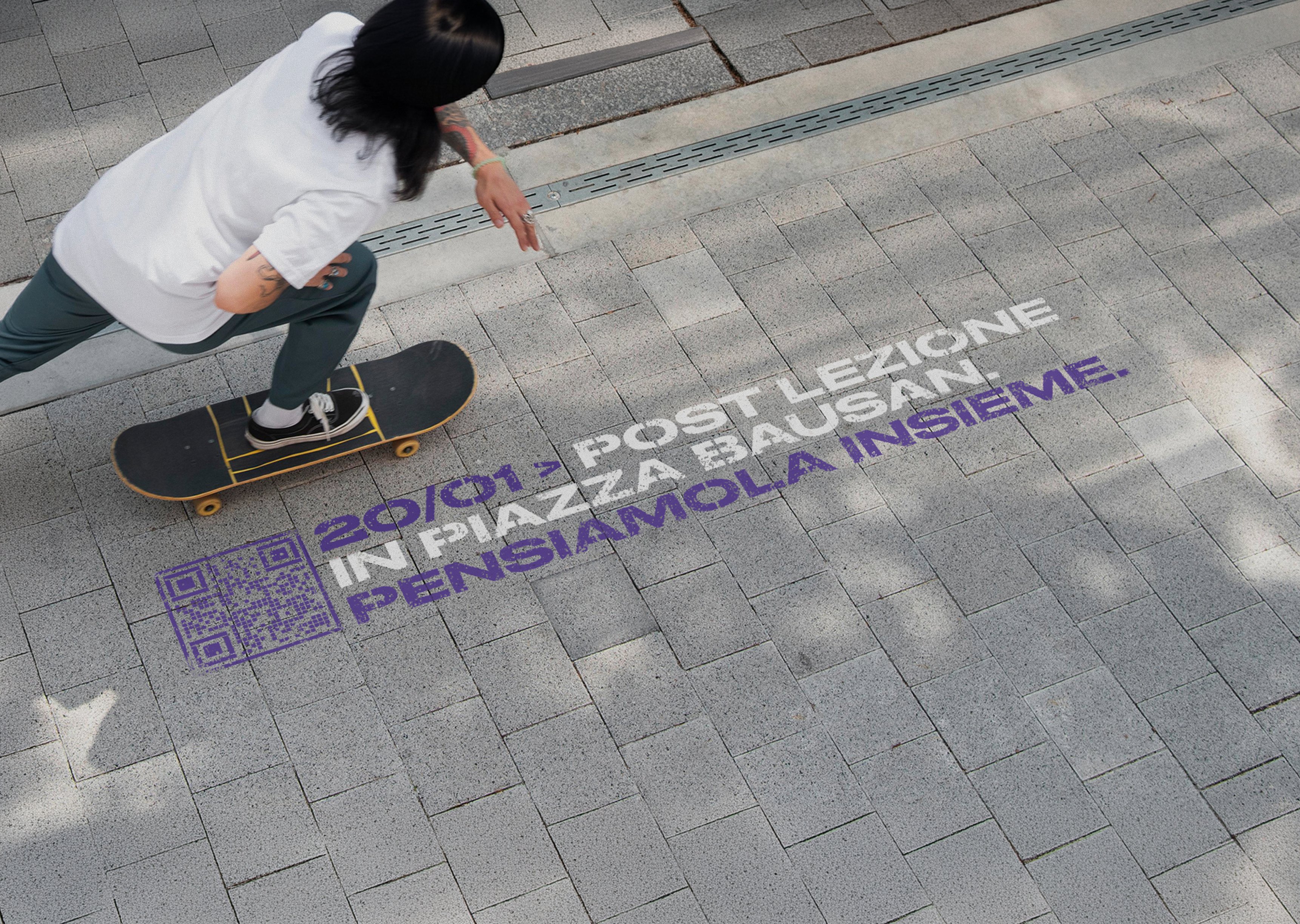 Floor graffiti Piazze Negate '20/01 POST LEZIONE IN PIAZZA BAUSAN. PENSIAMOLA INSIEME.' con QR code sulla pavimentazione, skater di passaggio